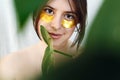 Happy girl with natural skin and lifting anti-wrinkle collagen patches under eyes and green palm leaf. Portrait of beautiful young Royalty Free Stock Photo