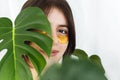 Happy girl with natural skin and lifting anti-wrinkle collagen patches under eyes and green palm leaf. Portrait of beautiful young Royalty Free Stock Photo