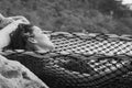 Happy girl on net hammock bed with flower behind ear relaxing by the sea Royalty Free Stock Photo