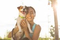 A happy girl owner with closed eyes holds her pet dog breed Jack Russell Terrier in arms lovingly in bliss, standing