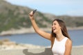 Happy girl photographing a selfie on the beach