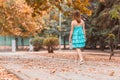 Happy girl playfully walks along autumn street in good mood. Dancing young woman in turquoise dress with beautiful legs. Freedom