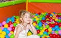 Happy girl playing in ball pit on birthday party in kids amusement park and indoor play center. Child playing with colorful balls Royalty Free Stock Photo