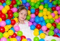 Happy girl playing in ball pit on birthday party in kids amusement park and indoor play center. Child playing with Royalty Free Stock Photo