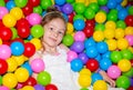 Happy girl playing in ball pit on birthday party in kids amusement park and indoor play center. Child playing with Royalty Free Stock Photo