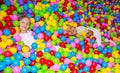 Happy girl playing in ball pit on birthday party in kids amusement park and indoor play center. Child playing with Royalty Free Stock Photo