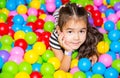 Happy girl playing in ball pit on birthday party in kids amusement park and indoor play center. Child playing with Royalty Free Stock Photo