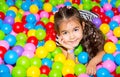 Happy girl playing in ball pit on birthday party in kids amusement park and indoor play center. Child playing with Royalty Free Stock Photo