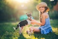 Happy girl playing with cute playful puppy little dog outdoor on a sunny day in a park Royalty Free Stock Photo