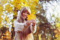 Happy girl playing with leaf, looking at camera and smilling. Autumn portrait woman hides her face yellow maple leaf Royalty Free Stock Photo