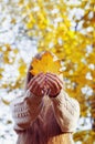 Happy girl playing with leaf, looking at camera and smilling. Autumn portrait woman hides her face yellow maple leaf Royalty Free Stock Photo