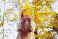 Happy girl playing with leaf, looking at camera and smilling. Autumn portrait woman hides her face yellow maple leaf Royalty Free Stock Photo