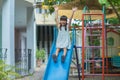 Happy girl playing on the slide. Happy little asian girl sliding and playing at outdoor playground in park on summer vacation. Royalty Free Stock Photo