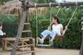 Happy girl playing on the wooden swing in the playground