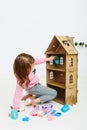 Happy girl plays with doll house and doll house furniture. Funny lovely child is having fun. Royalty Free Stock Photo