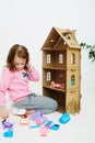 Happy girl plays with doll house and doll house furniture. Funny lovely child is having fun. Royalty Free Stock Photo