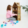 Happy girl plays with doll house and doll house furniture. Funny lovely child is having fun. Royalty Free Stock Photo