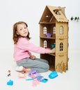 Happy girl plays with doll house and doll house furniture. Funny lovely child is having fun. Royalty Free Stock Photo