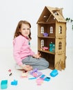 Happy girl plays with doll house and doll house furniture. Funny lovely child is having fun. Royalty Free Stock Photo