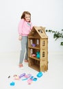 Happy girl plays with doll house and doll house furniture. Funny lovely child is having fun. Royalty Free Stock Photo