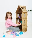 Happy girl plays with doll house and doll house furniture. Funny lovely child is having fun. Royalty Free Stock Photo