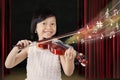 Happy girl plays violin on stage