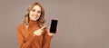 Happy girl pointing finger at mobile phone. Pointing index finger for advertising. Woman portrait, isolated header