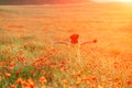 Happy girl poppy field walks under the evening sun. Back view