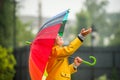 Happy girl portrait with bright rainbow umbrella. Children under the rain. Kid wearing yellow waterproof coat and boots Royalty Free Stock Photo