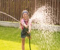 Happy girl pours water from a hose