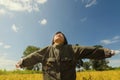 Happy girl with raised arms in green spring field against blue sky Royalty Free Stock Photo