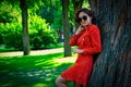 Happy girl in red dress leaning park tree in summer Royalty Free Stock Photo