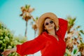 Happy girl in a red dress on vacation on the background of palm trees laughing and smiling. Vacation. Woman in sun glasses and big Royalty Free Stock Photo