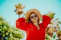 Happy girl in a red dress on vacation on the background of palm trees laughing and smiling. Vacation. Woman in sun glasses and big Royalty Free Stock Photo