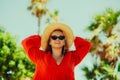 Happy girl in a red dress on vacation on the background of palm trees laughing and smiling. Vacation. A woman in sun glasses and a Royalty Free Stock Photo