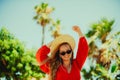 Happy girl in a red dress on vacation on the background of palm trees laughing and smiling. Vacation. A woman in sun glasses and a Royalty Free Stock Photo