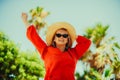 Happy girl in a red dress on vacation on the background of palm trees laughing and smiling. Vacation. A woman in sun glasses and a Royalty Free Stock Photo