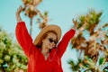 Happy girl in a red dress on vacation on the background of palm trees laughing and smiling. Vacation. A woman in sunglasses and a Royalty Free Stock Photo