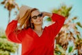 Happy girl in a red dress on vacation on the background of palm trees laughing and smiling. Vacation. A woman in sunglasses and a Royalty Free Stock Photo