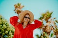 Happy girl in a red dress on vacation on the background of palm trees laughing and smiling. Vacation. A woman in sunglasses and a Royalty Free Stock Photo