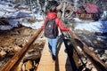 A happy girl, with a red jacket and a black backpack, crossing a wooden bridge Royalty Free Stock Photo