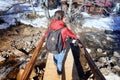 A happy girl, with a red jacket and a black backpack, crossing a wooden bridge Royalty Free Stock Photo