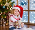 Happy girl in red santa hat opening Christmas gifts Royalty Free Stock Photo