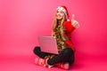 Happy girl in red sweater and Santa hat, sitting with laptop and Royalty Free Stock Photo