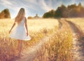 Happy girl on the road in a wheat field Royalty Free Stock Photo