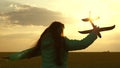 Happy girl runs with a toy airplane on a field in the sunset light. children play toy airplane. teenager dreams of