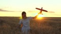 Happy girl runs with a toy airplane on a flower field. children play toy airplane. teenager dreams of flying and