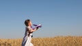 Happy girl runs with a toy airplane on a wheat field under a blue sky. children play a toy airplane. teenager dreams of
