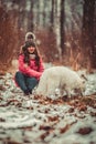 Happy girl with Samoyed dog in winter forest