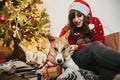 Happy girl in santa hat hugging with cute dog on background of g Royalty Free Stock Photo